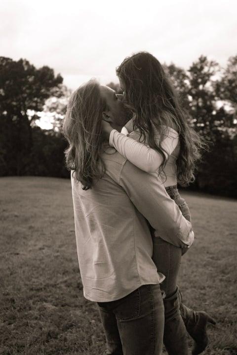 Two young women embracing in a grassy outdoor field