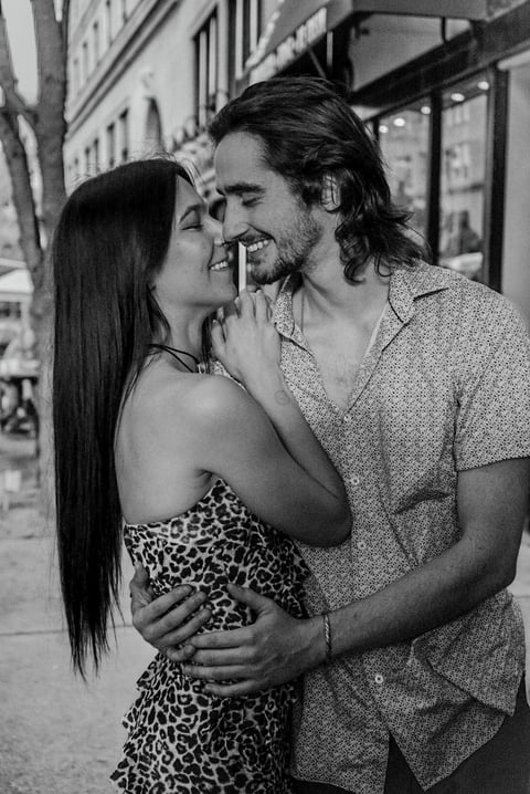 Black and white portrait of a couple smiling and embracing on a city street
