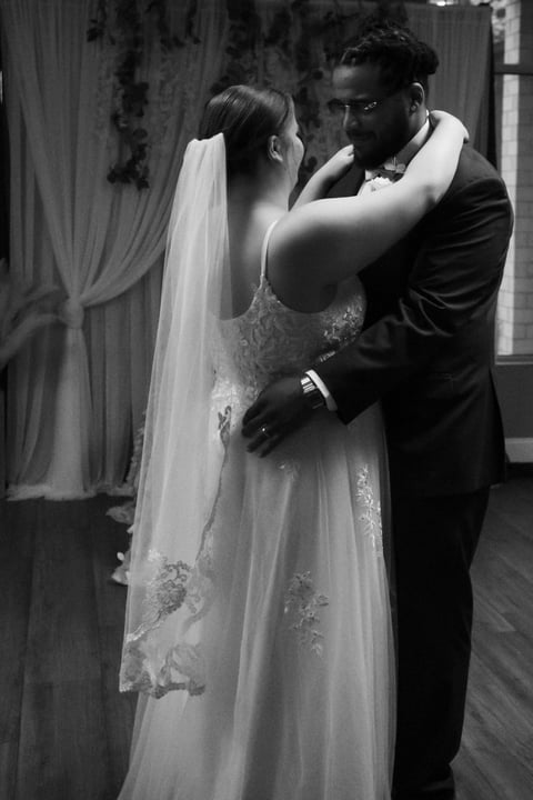 Black and white wedding photo of groom adjusting brides veil