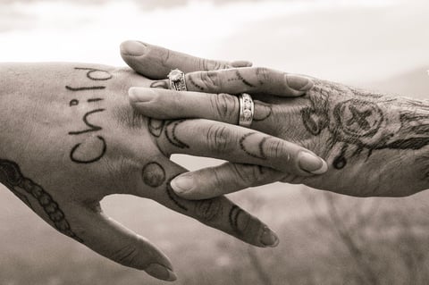 Close-up of two tattooed hands with wedding rings touching