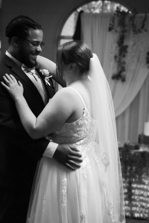 Bride and groom embracing at wedding ceremony in black and white photograph