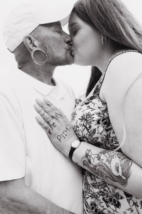 Black and white photo of a couple kissing with tattoos